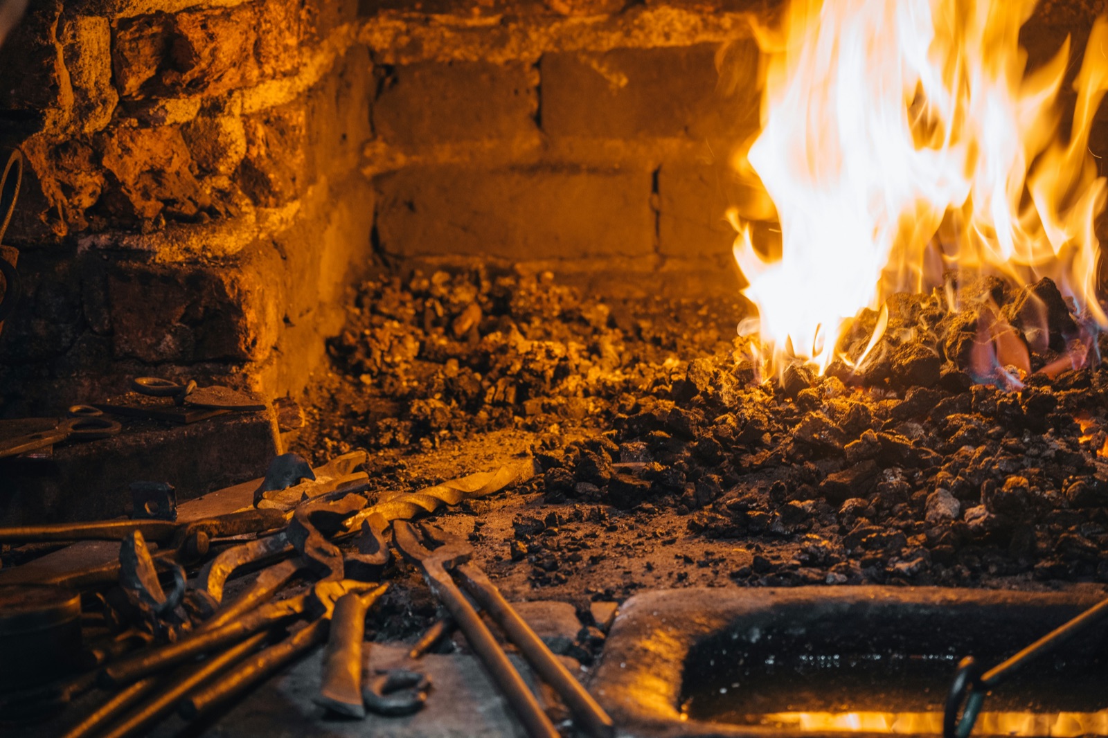 Blacksmith forge with glowing fire and tools for Epo-Weld™ HTCP ceramic putty high-temperature refractory patching