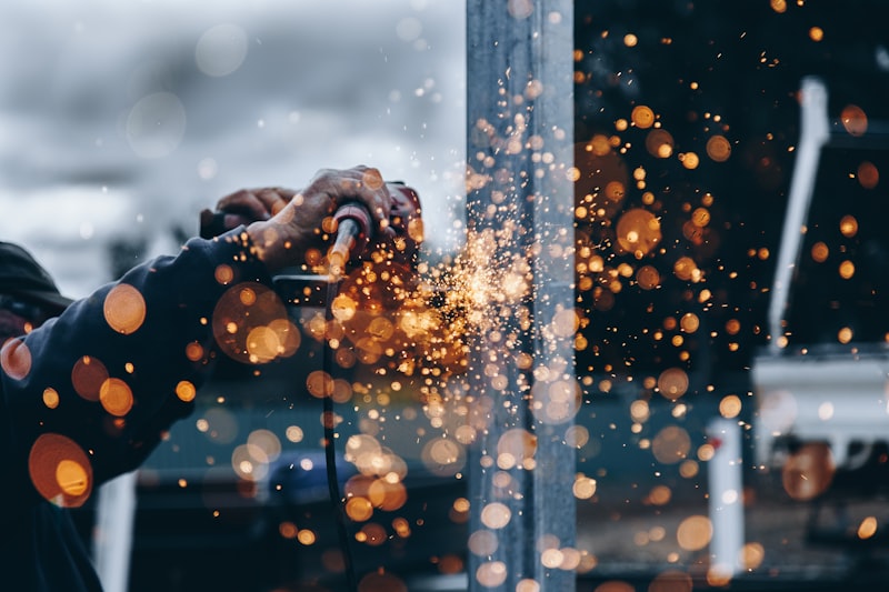 Worker grinding sparks off steel structural beam for Uni-Weld™ UV structural industrial bonding and metal assembly