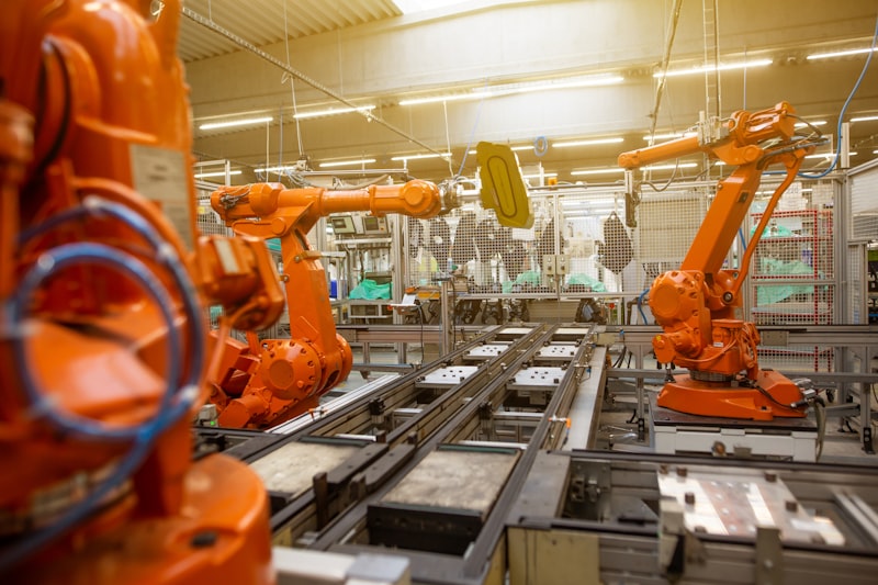 Orange industrial robotic arms on automated assembly line for Uni-Weld™ UV plastic bonder electronics assembly